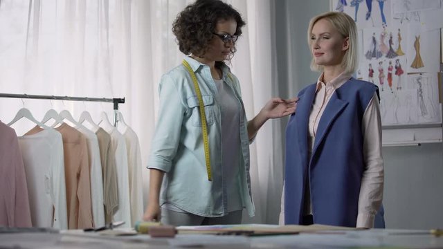 Seamstress customizing coat according to client, professional clothes modeling