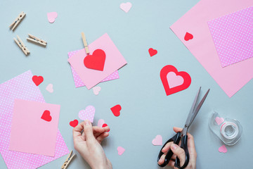 Valentines day background. Hands making Valentine card with heart and on the blue background