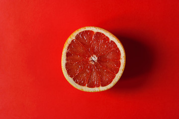 A circle of grapefruit on a bright red background. Place for text. Concept background. Flat lay. 
