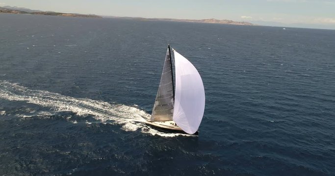 Aerial view of a sailing boat navigating with open sails off the coast of Porto Rotondo, Italy.