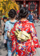 Two girls in a kimono on a city street, Tokyo, Japan. Vertical. Close-up. Back view.