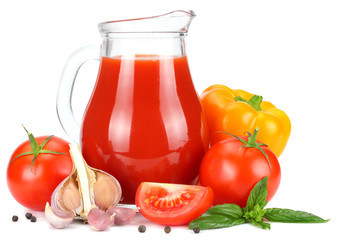 Tomato juice in glass jug with tomato, garlic, spices, and basil isolated on white background