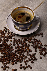A cup of coffee and coffee beans on a wooden background.