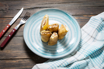 Pancakes with salmon and cream cheese on a wood background.