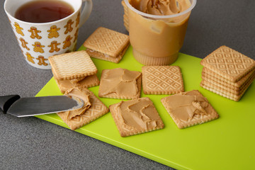 Peanut butter on cookies. Cookies with peanut butter on bright green board.