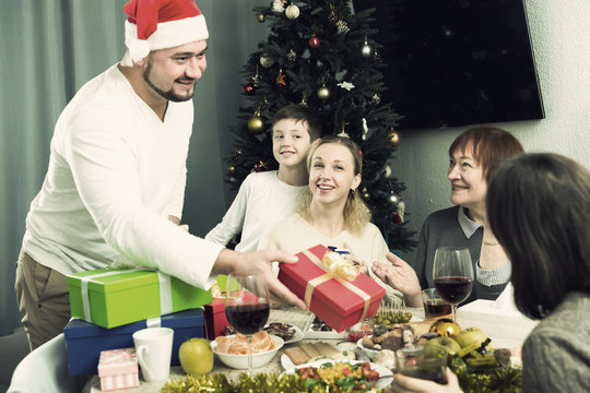 Smiling man giving Christmas presents to family