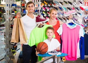 Obraz premium Couple with boy choosing shoes in sport shop