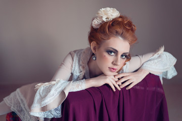 Young woman dressed in the fashion style of Rococo with vintage red hairstyle. Place for text	
