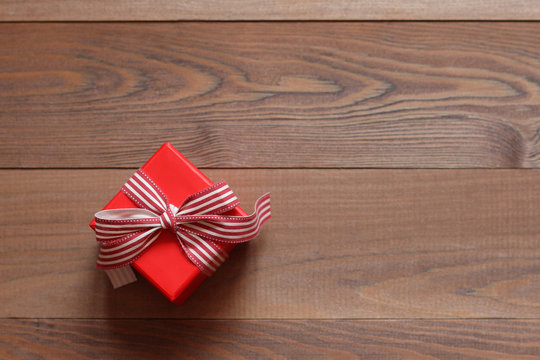 Red gift box with a tape on a wooden background