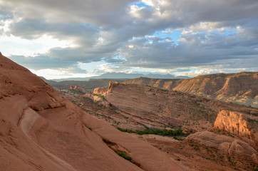 Fototapeta na wymiar blue sky and clouds over cliffs of Salt Valley at sunrise panoramic view from Delicate Arch Arches National Park, Moab, Utah