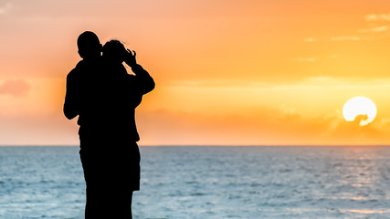 Silhouette eines Paares am Strand vor farbenprächtigen Sonnenaufgang