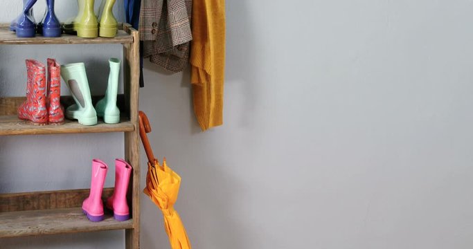 Umbrella, blazer, jumper and wellington boots on shoe rack 