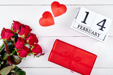 Valentines Day background with bouquet of red roses, gift box, two hearts and february 14 wooden block calendar, copy space. Greeting card mockup. Love concept. Top view, flat lay