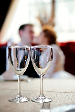 Two empty clear wine glasses are on the table in the background of couple in love. Close-up. Blurred the background. Vertical orientation