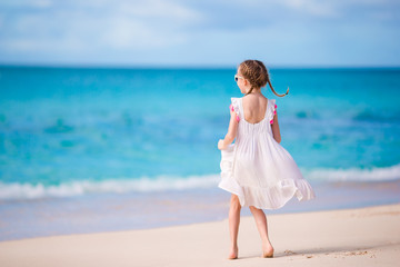 Fototapeta na wymiar Cute little girl in white dress at beach during caribbean vacation