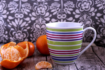Closeup a cup of herbal tea with tangerineson, on a wooden table . Health drink in the winter months.Prevention against cold. Blurred background.