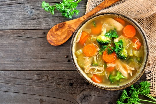 Homemade chicken vegetable soup, above view with copy space on a rustic wooden background