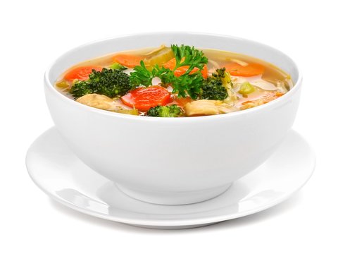Homemade chicken vegetable soup in a white bowl with saucer. Side view isolated on a white background.