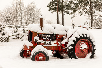 Old red tractor covered in snow