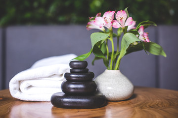 Dark stones for massage are stacked on top of each other on the table.