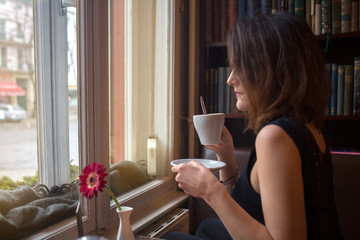 young woman with cup of coffee sitting by the window
