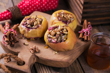 Obraz na płótnie Canvas Baked apples stuffed with berries, walnuts and honey on a wooden cutting board.