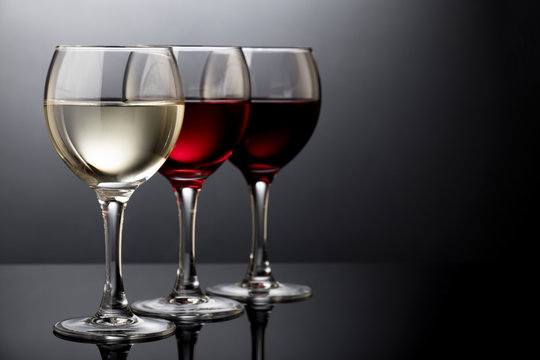 Elegant red, rose and white wine glasses in a black background