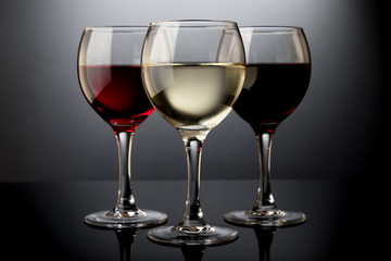 Red, rose and white wine glasses in a black background