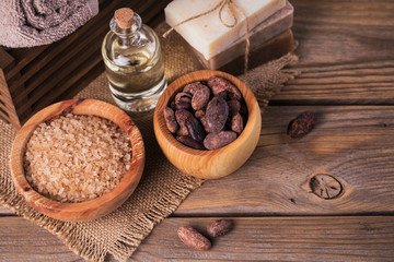 Natural cosmetic oil, sea salt and natural handmade soap with cocoa beans on rustic wooden background