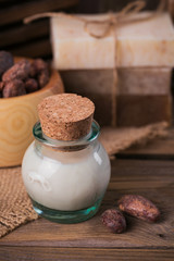 Natural cosmetic oil, sea salt and natural handmade soap with cocoa beans on rustic wooden background