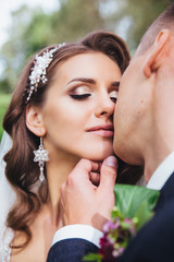 Beautiful newlywed bride and groom in park face close-up