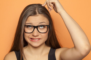 young pensive girl scratching her head with finger