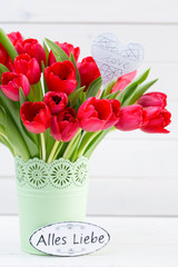 Fresh red tulip flowers bouquet on shelf in front of wooden wall.