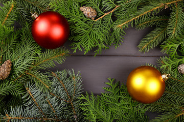 Christmas background, decor, attributes, on a wooden background. Set of fresh fir branches and ornaments of red and gold balls. Cones and bells.