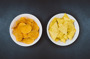 Party snacks - potato chips and snacks in bowl on black slate table. Photograph taken from above, top view with copy space around products.