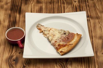 a piece of pizza capricciosa on a plate served with ketchup