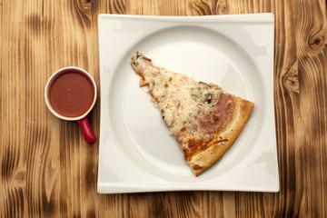 a piece of pizza capricciosa on a plate served with ketchup