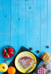 Fresh homemade crepes served on a plate with strawberries and blueberries, on a light blue wooden background,  free space for text.