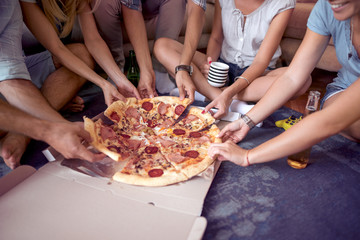 Image of  friends hands taking slices of pizza.