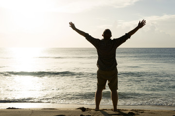 Fototapeta premium Man with Outstretched Arms Facing the Sun and Ocean