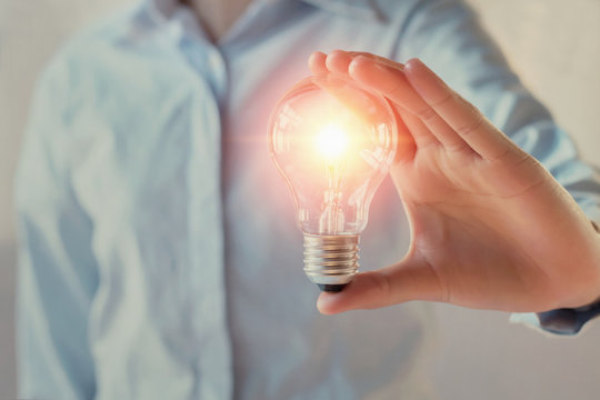 businesswoman holding light bulb, innovation and inspiration concept