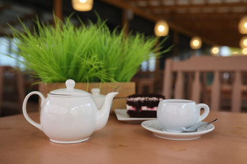 Kettle with a drink and dessert in a street cafe. Tea in the ket