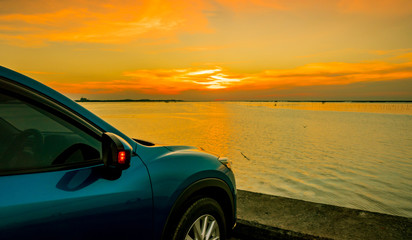 Fototapeta na wymiar Blue compact SUV car with sport and modern design parked on concrete road by the sea at sunset. Environmentally friendly technology. Business success concept.