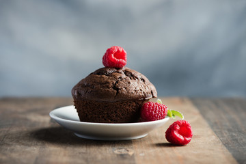 Chocolate muffins or cupcakes with raspberries, healthy breakfast, homemade snack, selective focus, toned image.