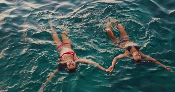 Beautiful girls relaxing floating in the ocean at sunset