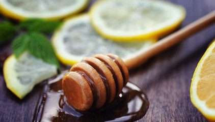 Honey and lemon. Honey stick and slices of sliced lemon on a woo