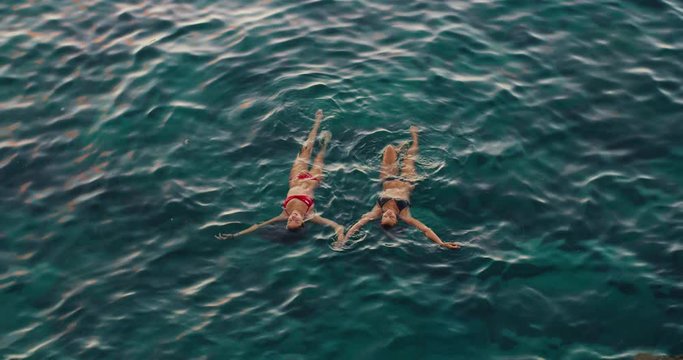 Beautiful girls relaxing floating in the ocean at sunset