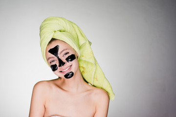 happy woman with a towel on her head apply mask on problem areas