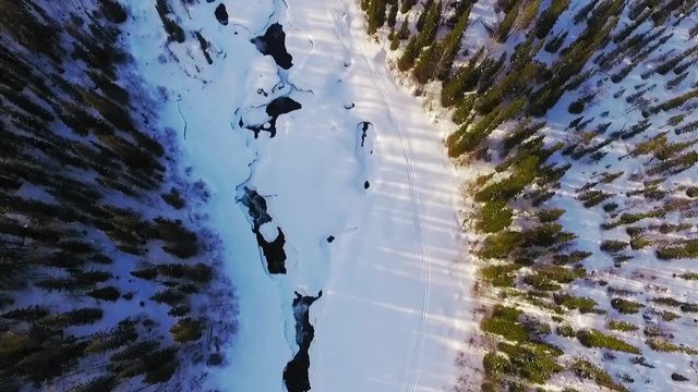 Aerial video of river then looking up, revealing mountains and a beautiful winter landscape.