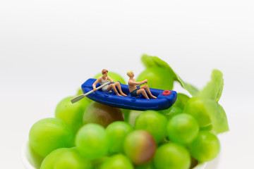 Miniature people : Travelers with paddle boat on the grape. Image use for activities, travel business concept.